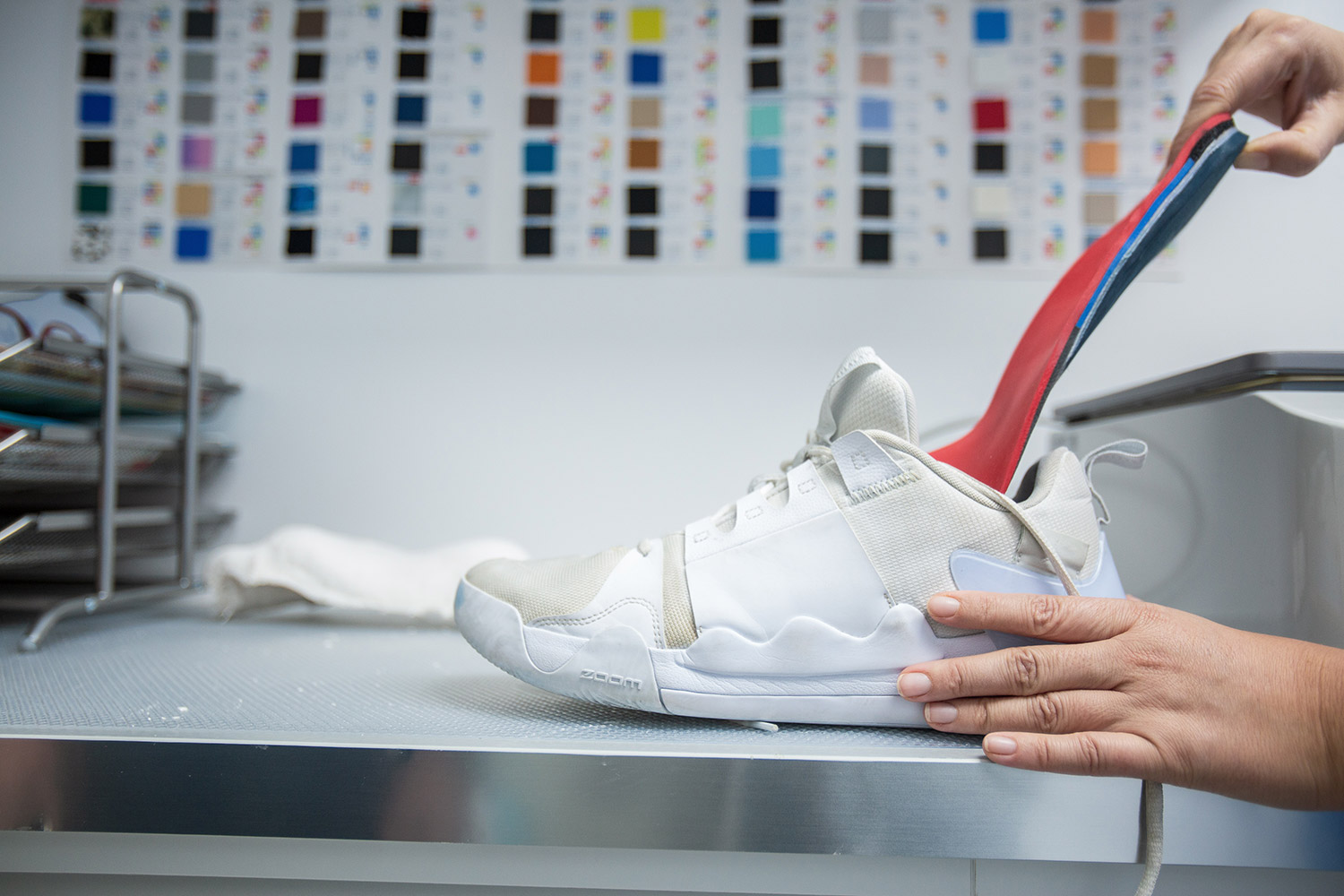 Plantilla deportiva colocada dentro de una zapatilla, con el muestrario de materiales al fondo